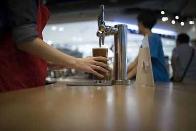 Midsection of female worker preparing coffee in cafe