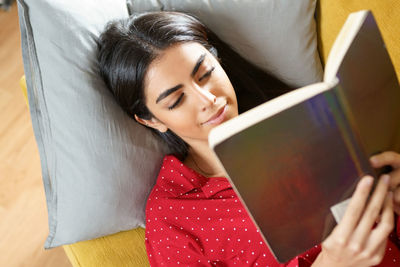 High angle view of woman lying on book at home