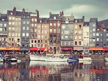 Boats moored at harbor against buildings in city