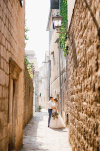 Side view of couple in alley amidst buildings