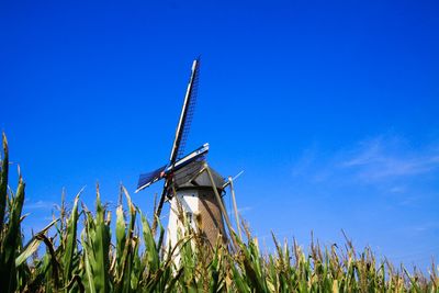 Low angle view of windmill on field against clear blue sky