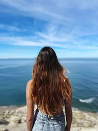 Rear view of woman standing at beach