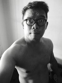 Portrait of shirtless man wearing eyeglasses at home