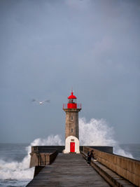 Lighthouse by sea against sky