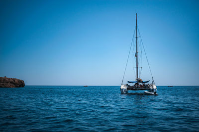 Sailboat sailing in sea against clear blue sky