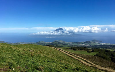 Scenic view of mountains and sea against blue sky