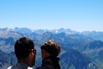 Rear view of father carrying son against mountain range