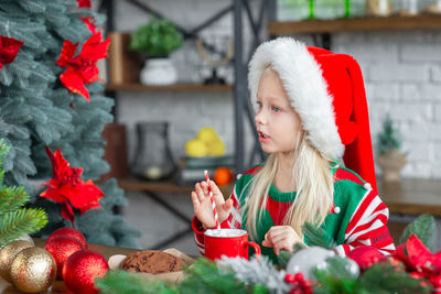 Cute little child girl eating sweet cookies and drinking hot chocolate