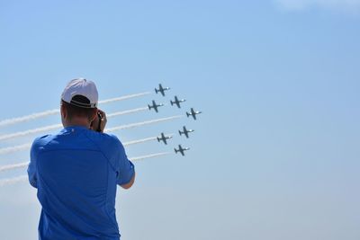 Rear view of man photographing air show