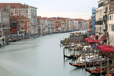 Boats moored in canal amidst buildings in city