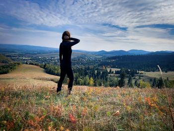 Full body shot of woman wearing sports clothes and looking at the mountains in front of her