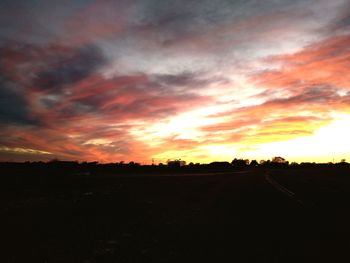 Scenic view of silhouette field against orange sky