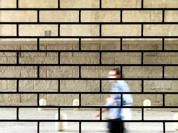 Blurred motion of mature man walking on footpath seen through window