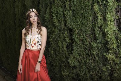 Portrait of a young woman standing against plants