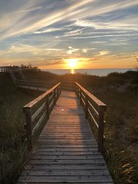 Boardwalk leading towards  sky during sunset