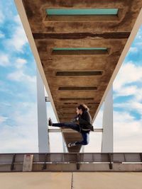 Low angle view of young man sitting against sky