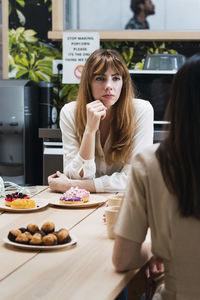 Businesswoman looking at colleague discussing in cafeteria