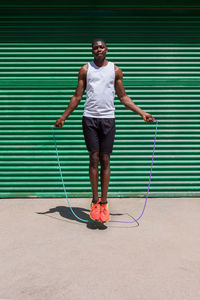 Focused african american male athlete jumping rope during cardio workout on sunny day in city