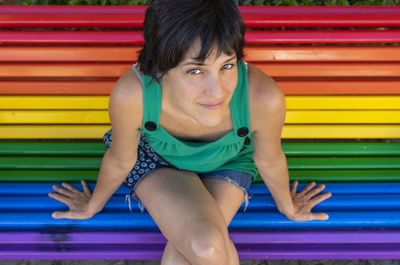 Portrait of young woman sitting on multi colored umbrella