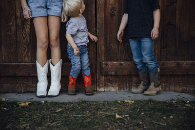Siblings standing by wooden door