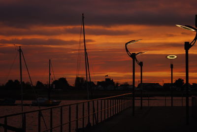 Silhouette street lights against sky during sunset