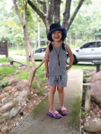 Portrait of cute girl standing on seat against trees