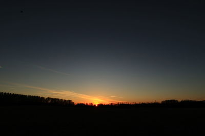 Scenic view of silhouette field against clear sky at sunset