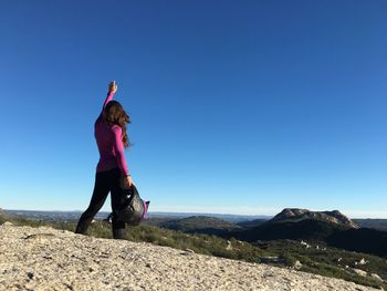 Full length of woman standing on mountain against clear blue sky