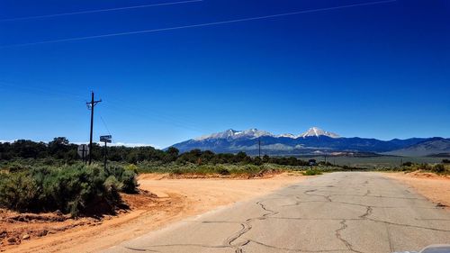 Road by mountains against clear blue sky