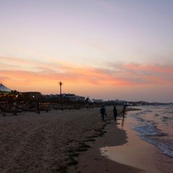 Silhouette people on beach against sky during sunset