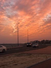 Cars on road against dramatic sky during sunset