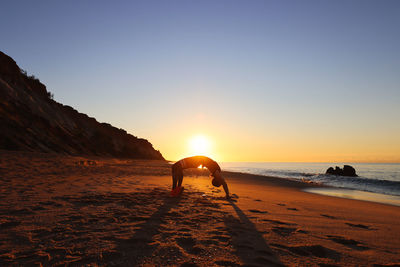 Scenic view of beach against clear sky during sunset