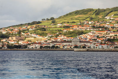 Aerial view of townscape by sea against sky