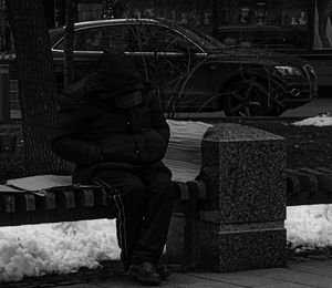 Rear view of woman sitting in snow