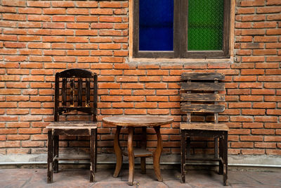 Empty chairs and table against brick wall