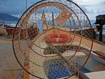 Close-up of fishing net on boat against sky