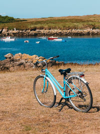 Bicycle on shore by sea against sky