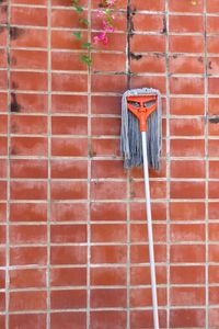 Close-up of mop leaning on brick wall