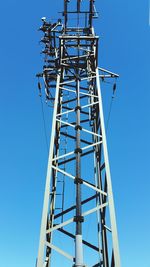 Low angle view of communications tower against clear blue sky