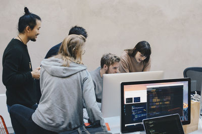 Male and female computer programmers using desktop pc in creative office