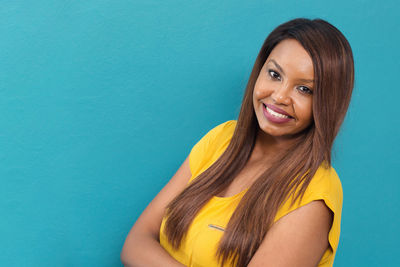 Portrait of smiling young woman against blue background