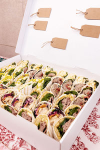 Abundance of tasty tortilla rolls with different fillings served on table with colorful tablecloth near wall during festive event