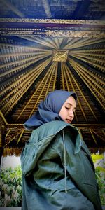 Low angle view of woman standing against patterned ceiling