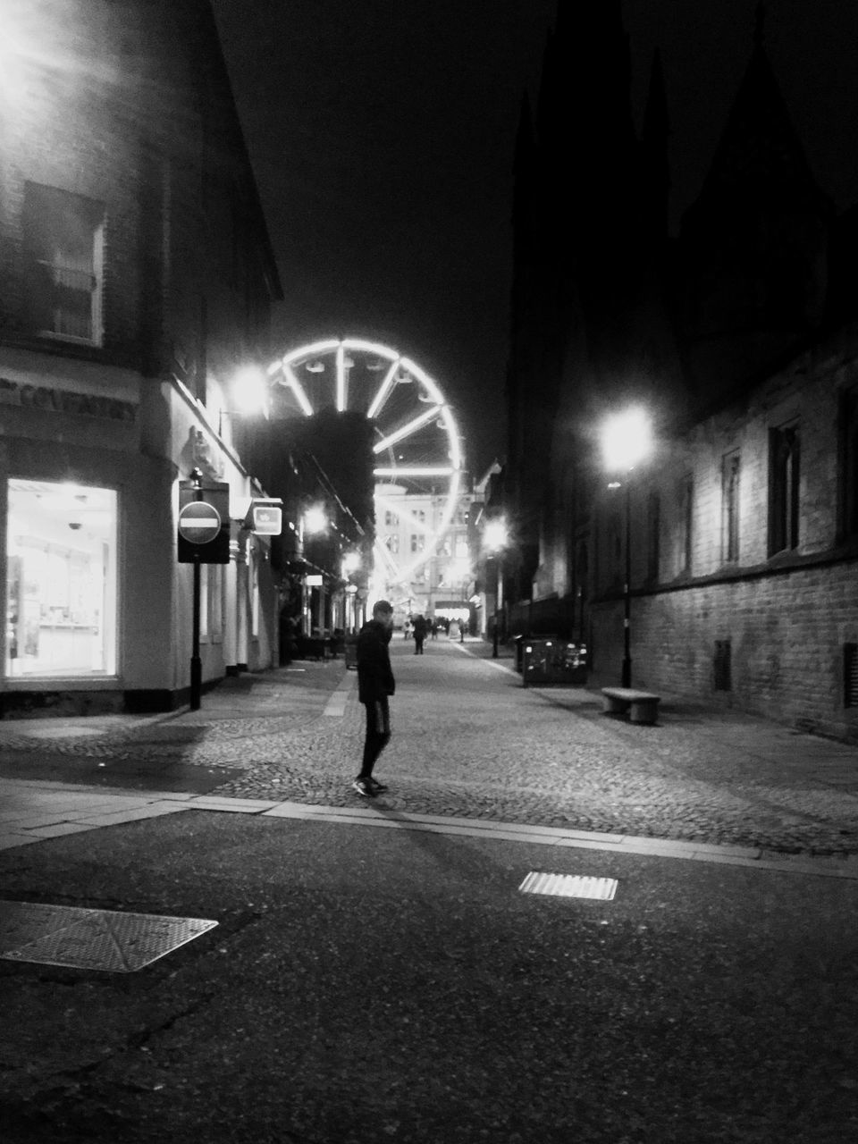 MAN WALKING ON ILLUMINATED STREET