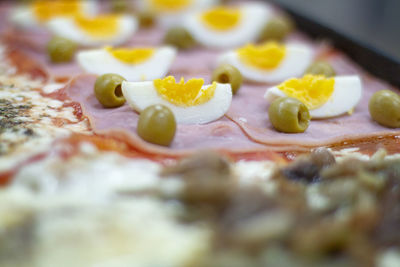 Pizza with hard boiled eggs and olives.