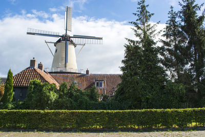 Traditional windmill by building against sky