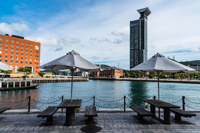 Pier on sea by buildings against sky