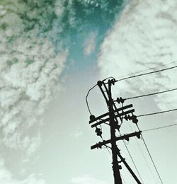 Low angle view of power lines against cloudy sky