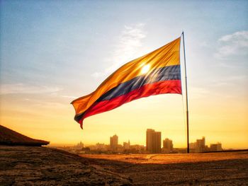 Flag against sky in city during sunset