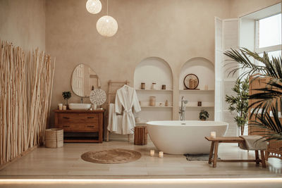 Luxury interior of big bathroom at modern african style with oval bathtub in natural lighting